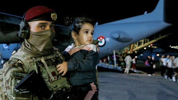 A soldier carries a child as people evacuated from Sudan disembark from an aircraft at a military airport in Amman - Sputnik Africa