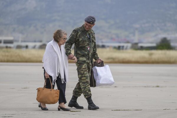 A Greek air force soldier helps a passenger from Sudan after disembarking from a military plane at Elefsina Air Force Base in western Athens, Greece, on Tuesday, 25 April 2023. - Sputnik Africa