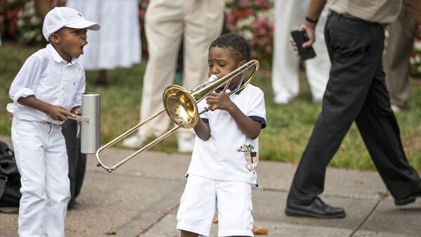 Un garçon avec un trombone lors d'une réunion dominicale à la United House of Prayer for All People à Washington DC - Sputnik Afrique