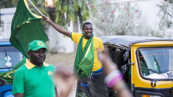 A Chama Cha Mapinduzi (CCM) supporter waves a flag while riding in a bajaj (tuk-tuk) in downtown Dar es Salaam on October 22, 2015 - Sputnik Africa