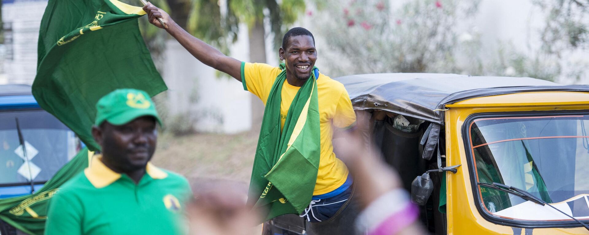 A Chama Cha Mapinduzi (CCM) supporter waves a flag while riding in a bajaj (tuk-tuk) in downtown Dar es Salaam on October 22, 2015 - Sputnik Africa, 1920, 02.05.2023