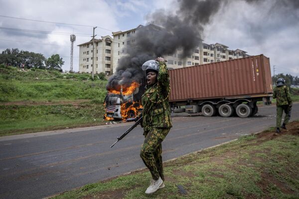 A riot policewoman calls for reinforcements to come after opposition protesters set fire to a truck after failing to open the container it was transporting, during clashes in the Kibera slum of the capital Nairobi, Kenya Tuesday, May 2, 2023.  - Sputnik Africa