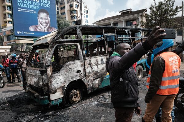 A man takes a selfie in front of a burnt bus as the Kenya opposition leader Raila Odinga&#x27;s Azimio la Umoja coalition calls for new demonstrations in Nairobi on May 2, 2023. - Sputnik Africa
