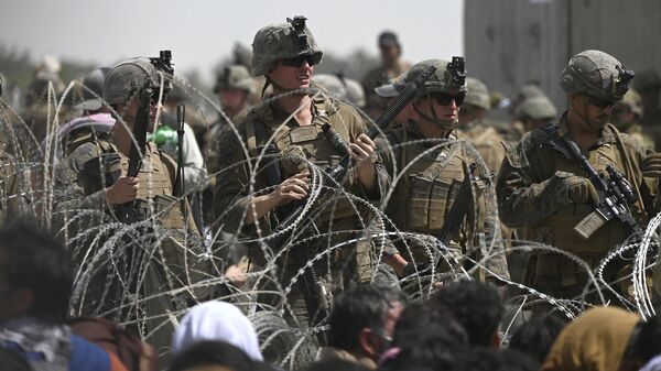 US soldiers stand guard behind barbed wire as Afghans sit on a roadside near the military part of the airport in Kabul on August 20, 2021, hoping to flee from the country after the Taliban's military takeover of Afghanistan - Sputnik Africa