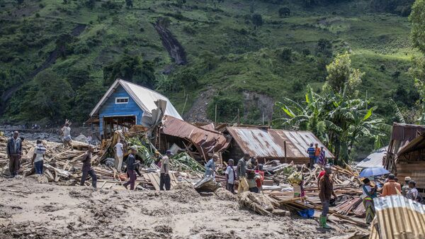 People walk next to houses destroyed by the floods in the village of Nyamukubi, South Kivu province, in Congo Saturday, May 6, 2023. - Sputnik Africa