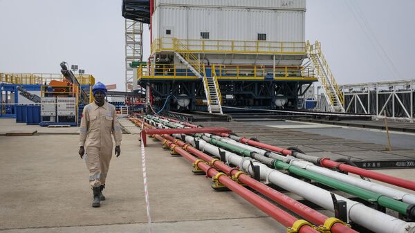 A Ugandan worker from China Oilfield Services Limited (COSL), a contractor for China National Offshore Oil Corporation (CNOOC), walks by pipes near the drilling rig at the Kingfisher oil field on the shores of Lake Albert in the Kikuube district of western Uganda Tuesday, Jan. 24, 2023. - Sputnik Africa