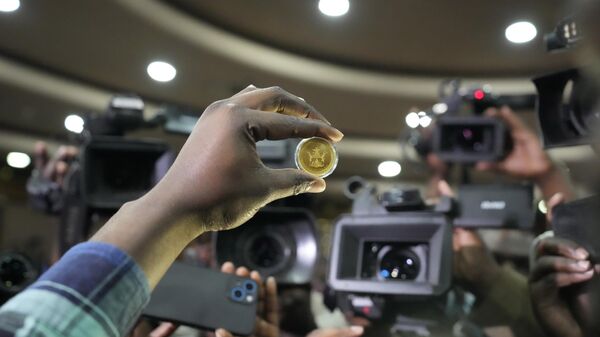 A reserve bank of Zimbabwe offical holds a sample of a gold coin at the launch in Harare, Monday, July, 25, 2022. Zimbabwe has launched gold coins to be sold to the public in a bid to to tame runaway inflation that has further eroded the country's unstable currency - Sputnik Africa