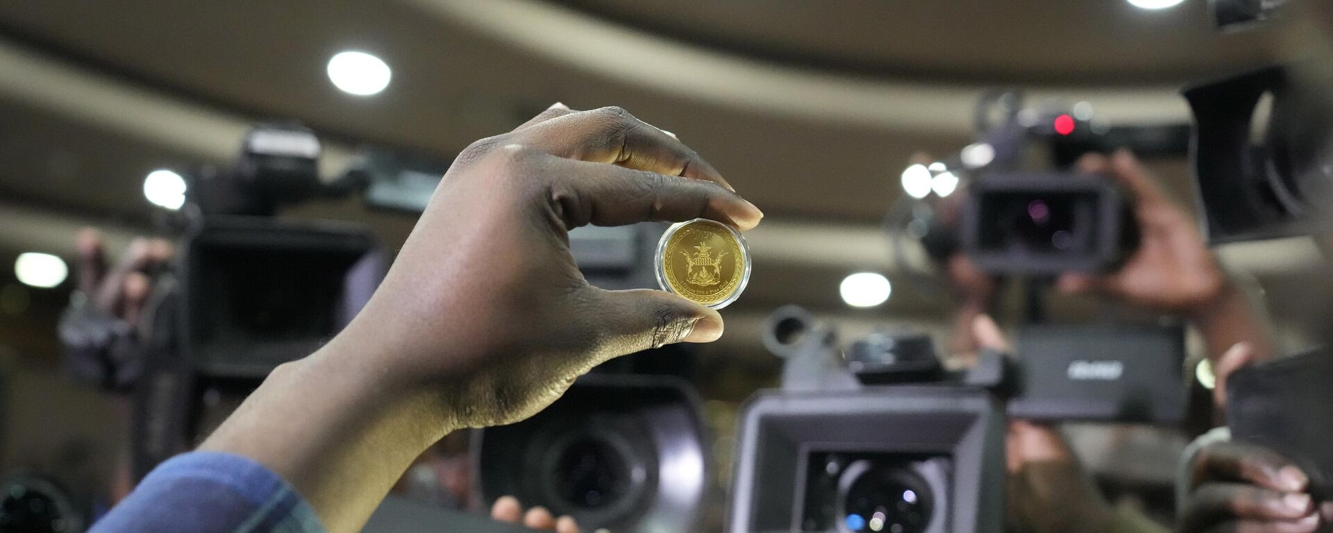 A reserve bank of Zimbabwe offical holds a sample of a gold coin at the launch in Harare, Monday, July, 25, 2022. Zimbabwe has launched gold coins to be sold to the public in a bid to to tame runaway inflation that has further eroded the country's unstable currency - Sputnik Africa, 1920, 13.05.2023