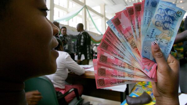 A woman in Accra holds a wad of new currency, the new cedi, which Ghana put into circulation on July 03, 2007, - Sputnik Africa