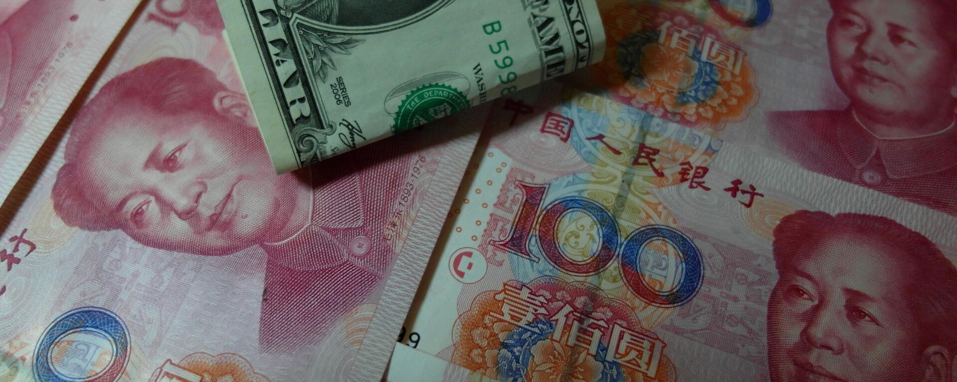 Yuan banknotes and US dollars are seen on a table in Yichang, central China's Hubei province on August 14, 2015 - Sputnik Africa, 1920, 19.05.2023