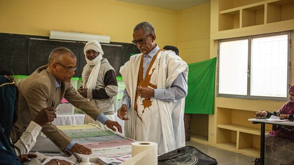 A man confirms his name with polling station officials at a polling station in Nouakchott on May 13, 2023.  - Sputnik Africa