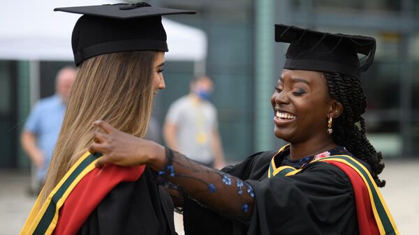 Students smile after after taking part in a Covid-safe, in-person graduation ceremony at the University of Bolton, northwest England on July 9, 2021.  - Sputnik Africa