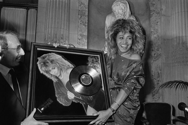 US singer Tina Turner receives the Golden record award from Pathe Marconi chairman Guy Deluz (L) on October 8, 1986 in Paris.  - Sputnik Africa