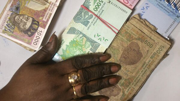 Une caissière de banque compte des piles de nouveaux billets de banque en francs CFA d'Afrique de l'Ouest ainsi que des billets de 500 CFA à l'ancienne, en bas à droite, et des billets de 10 000 CFA à l'ancienne, en haut à gauche, dans une banque de Dakar, au Sénégal, le lundi 13 septembre 2004. L'Afrique occidentale française est engagée dans une campagne massive regroupant huit pays pour retirer plus d'un milliard d'euros (dollars) en monnaie vieillie et molle. - Sputnik Afrique