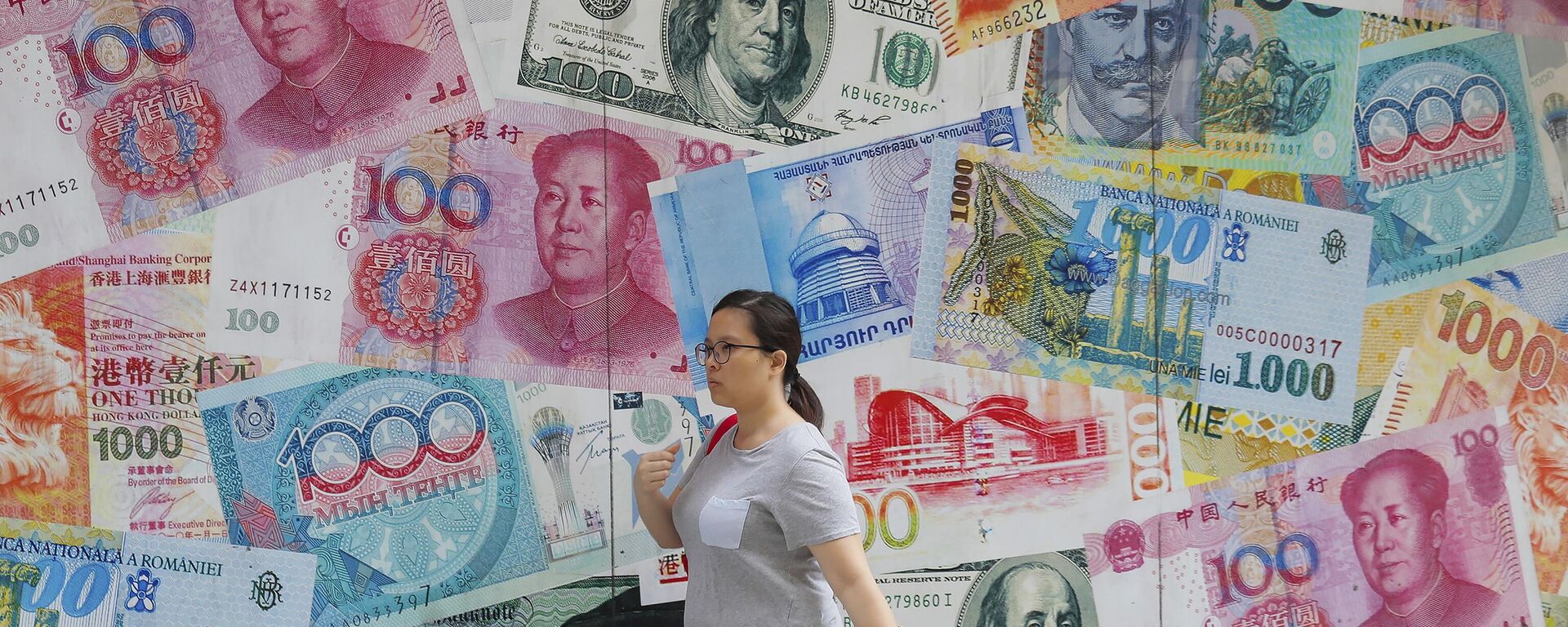  A woman walks by a money exchange shop decorated with different countries currency banknotes at Central, a business district in Hong Kong, Aug. 6, 2019. - Sputnik Africa, 1920, 22.08.2023