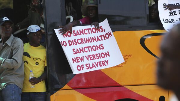 A woman on a bus holds a placard while protesting over U.S. sanctions that the Zimbabwean government blames for the country's worsening economic problems, in Harare, Friday, Oct, 25, 2019. The Zimbabwe government blames U.S. sanctions for devastating economic conditions, galloping inflation and severe shortages of basic goods, but the U.S. blames corruption, financial mismanagement and human rights violations instead - Sputnik Africa