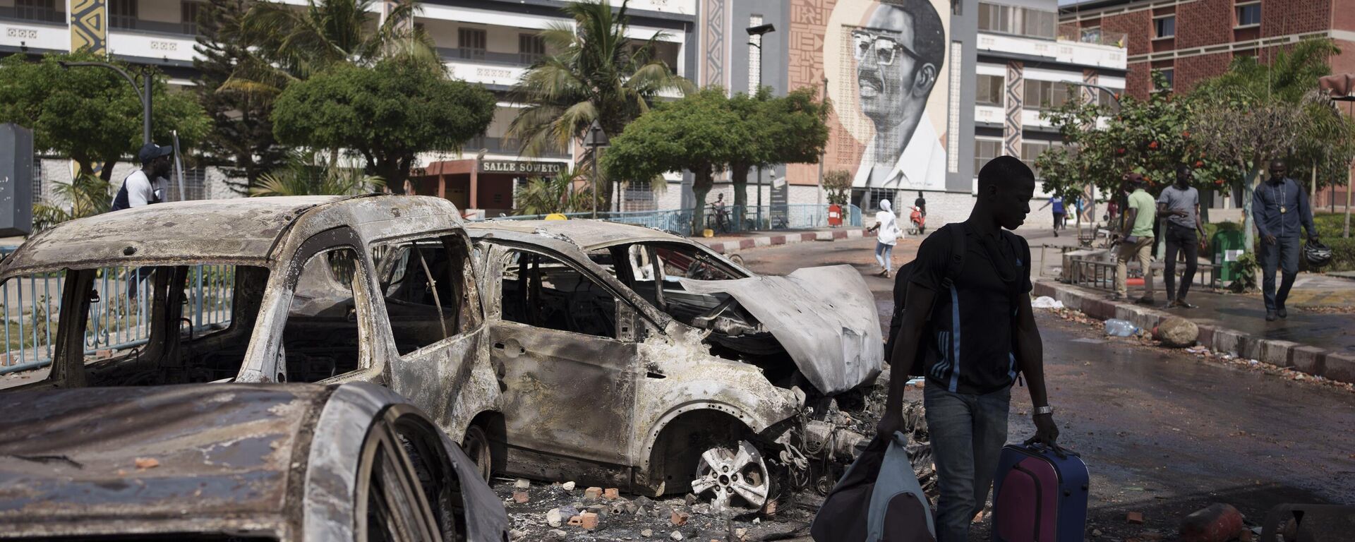 A student carrying his belongings walks past burned cars as he leaves the Cheikh Anta Diop University after authorities ordered the institution to be closed until further notice, amid clashes between police and supporters of Senegalese opposition leader Ousmane Sonko, in Dakar, Senegal, Friday, June 2, 2023. - Sputnik Africa, 1920, 06.06.2023
