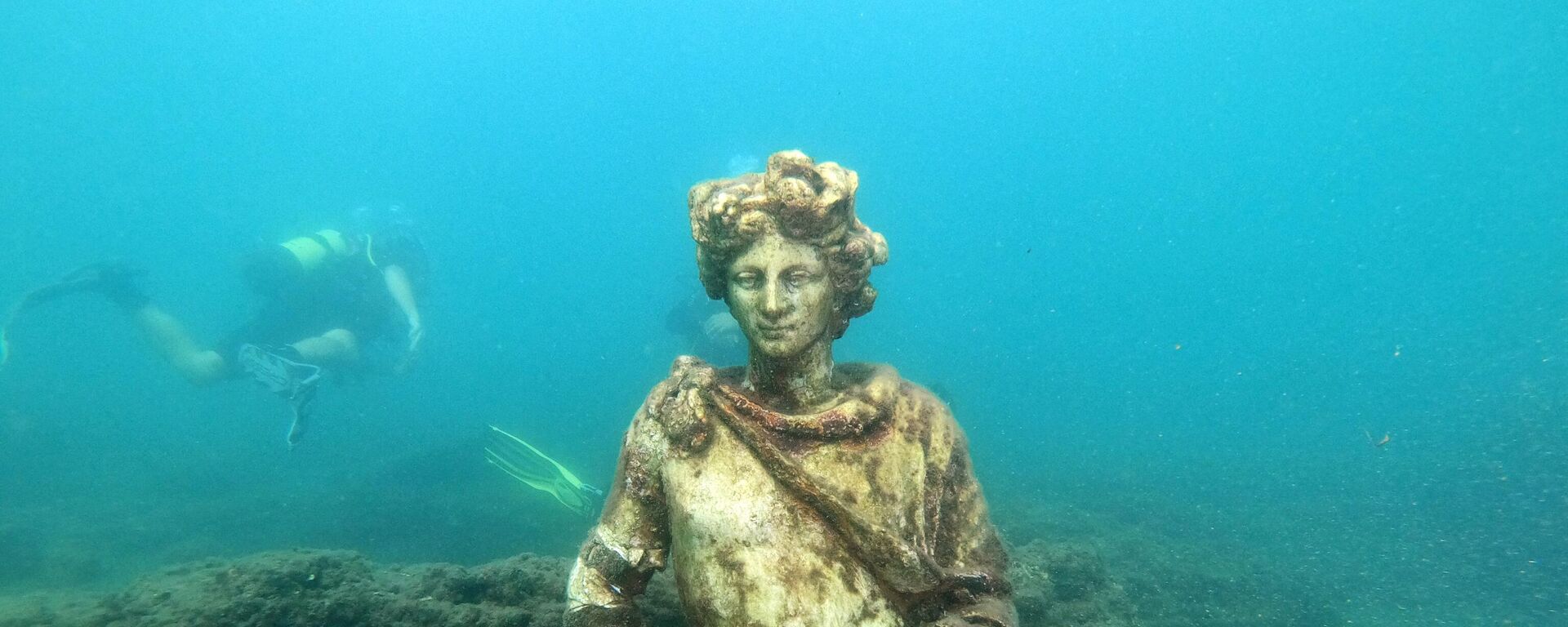 In this photograph taken on August 18, 2021 a dive guide shows tourists a copy of the original statue preserved at the Museum of Baiae, representing Dionysus with ivy crown in the Nymphaeum of punta Epitaffio, the submerged ancient Roman city of Baiae at the Baiae Underwater Park, part of the Campi Flegrei Archaeological Park complex site in Pozzuoli near Naples.  - Sputnik Africa, 1920, 08.06.2023