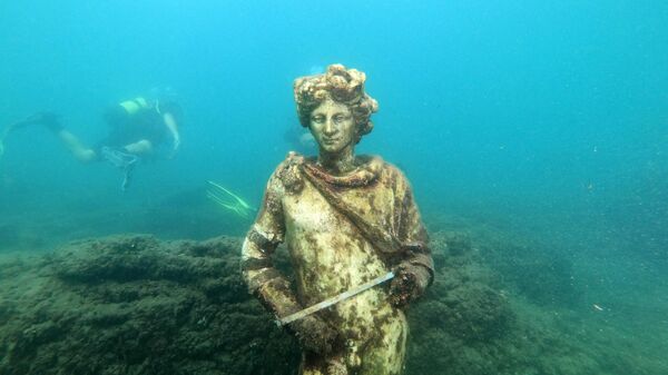In this photograph taken on August 18, 2021 a dive guide shows tourists a copy of the original statue preserved at the Museum of Baiae, representing Dionysus with ivy crown in the Nymphaeum of punta Epitaffio, the submerged ancient Roman city of Baiae at the Baiae Underwater Park, part of the Campi Flegrei Archaeological Park complex site in Pozzuoli near Naples.  - Sputnik Africa