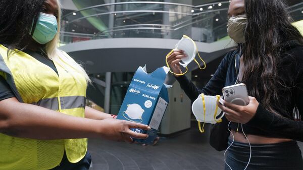 MTA employee Shanita Hancle, left, hands out masks to commuters at the entrance to a subway station in New York, Thursday, June 8, 2023.  - Sputnik Africa