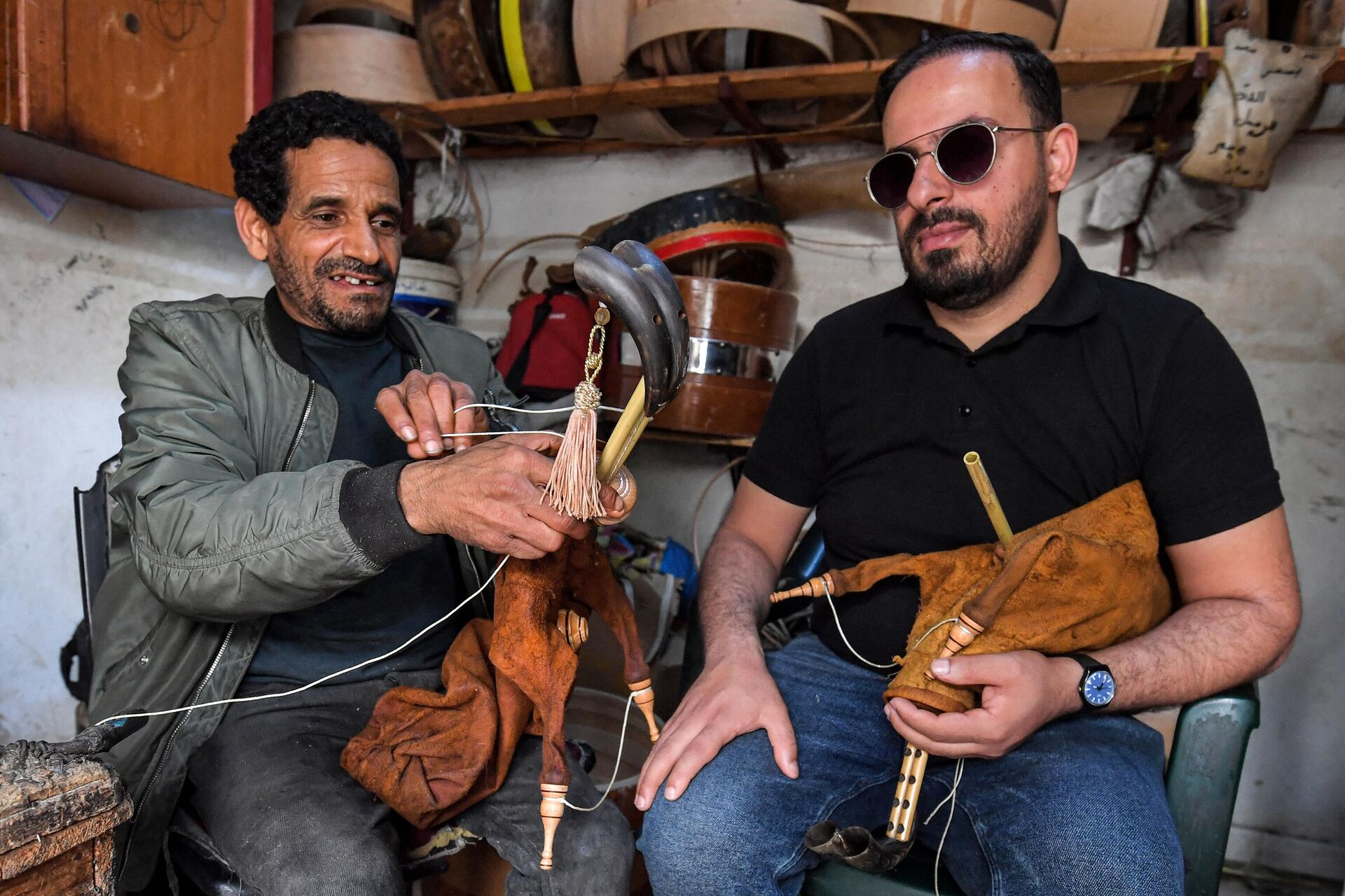 In this picture taken on May 24, 2023, Tunisian craftsman Khaled ben Khemis (L) fabricates a mizwad instrument as musician Montassar Jebali tests another at a traditional workshop in the locality of Jedaida near Tunis.  - Sputnik Africa, 1920, 12.06.2023