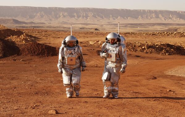 A couple of astronauts from a team from Europe and Israel walk in spacesuits during a training mission for planet Mars at a site that simulates an off-site station at the Ramon Crater in Mitzpe Ramon in Israel&#x27;s southern Negev desert on October 10, 2021.  - Sputnik Africa