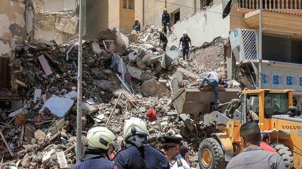 La défense civile s'entretiennent avec un policier sur les lieux de l'effondrement d'un immeuble de 13 étages dans le district de Sidi Bishr à Alexandrie, dans le nord de l'Égypte, le 26 juin 2023. - Sputnik Afrique