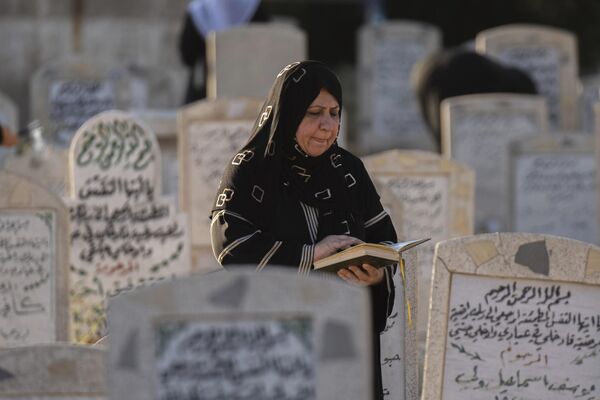 An Iraqi woman reads from the Quran at the grave of a relative, during the first day of the Muslim feast of Eid al-Adha in a Ghazali cemetery in Baghdad, Iraq, Wednesday, June 28, 2023. - Sputnik Africa