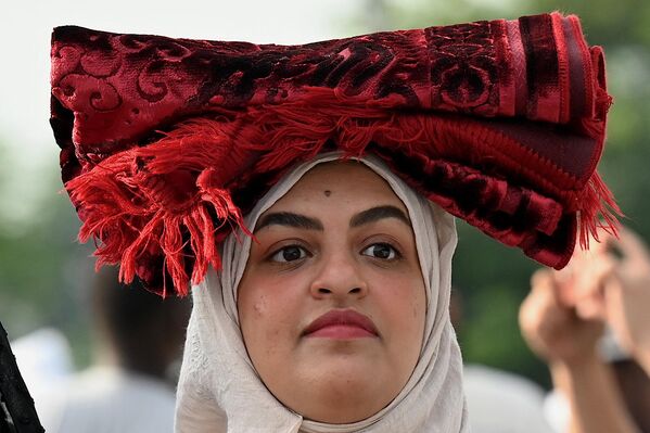 A woman carries her prayer rug on her head as she takes part in a morning prayer celebrating the Muslim feast of Eid al-Adha at the Quirino Grandstand in Manila on June 28, 2023. - Sputnik Africa