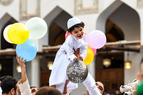 A boy reacts while holding balloons as he is lifted by a man after the morning prayers for Eid al-Adha at the historic Azhar mosque in the center of Egypt&#x27;s Cairo on June 28, 2023. - Sputnik Africa