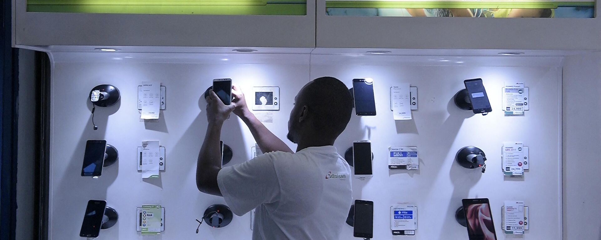 An employee arranges a display of smartphones at a Safaricom shop in Nairobi on November 22, 2018. - Sputnik Africa, 1920, 06.07.2023