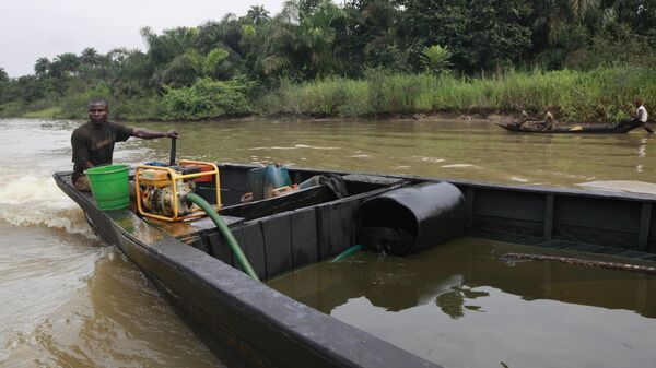 A suspected oil thief rides a wooden boat full of stolen crude oil on the creeks of Bayelsa, Nigeria - Sputnik Africa