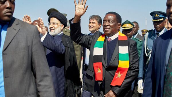 Zimbabwe President Emmerson Mnangagwa (R) waves next to Iranian President Ebrahim Raisi (L) who arrived on a state visit at the Robert Gabriel Mugabe International Airport in Harare on July 13, 2023 - Sputnik Africa