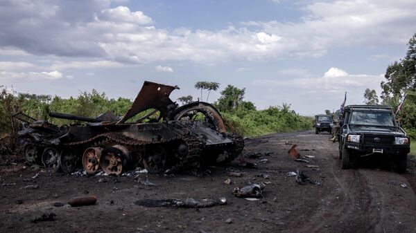This photograph taken on January 6, 2023 shows cars passing by a destroyed military vehicle in Rugari, after clashes between the Congolese army and M23 rebels in the east of the Democratic Republic of Congo - Sputnik Africa