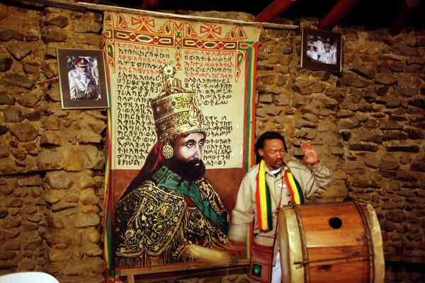 A Rastafarian plays drums during an early morning religious ceremony, with the face of Emperor of Ethiopia Haile Selassie I, left, seen in Knysna, South Africa, Tuesday, May 10,  2016. Rastafarianism is an Abrahamic religion originating from Jamaica around 1930, with adherents believing former Emperor of Ethiopia Haile Selassie I is their savior. - Sputnik Africa