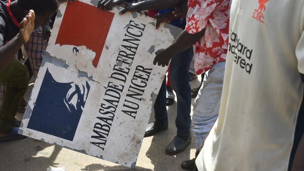 Protesters hold a sign taken from the French Embassy in Niamey during a demonstration that followed a rally in support of Niger's junta in Niamey on July 30, 2023 - Sputnik Africa