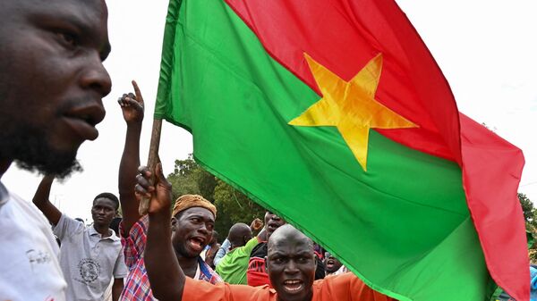 Supporters of Burkina Faso's new leader Ibrahim Traore hold a national flag during a demonstration near the national radio and television headquarters (RTB) in Ouagadougou on October 6, 2022 - Sputnik Africa