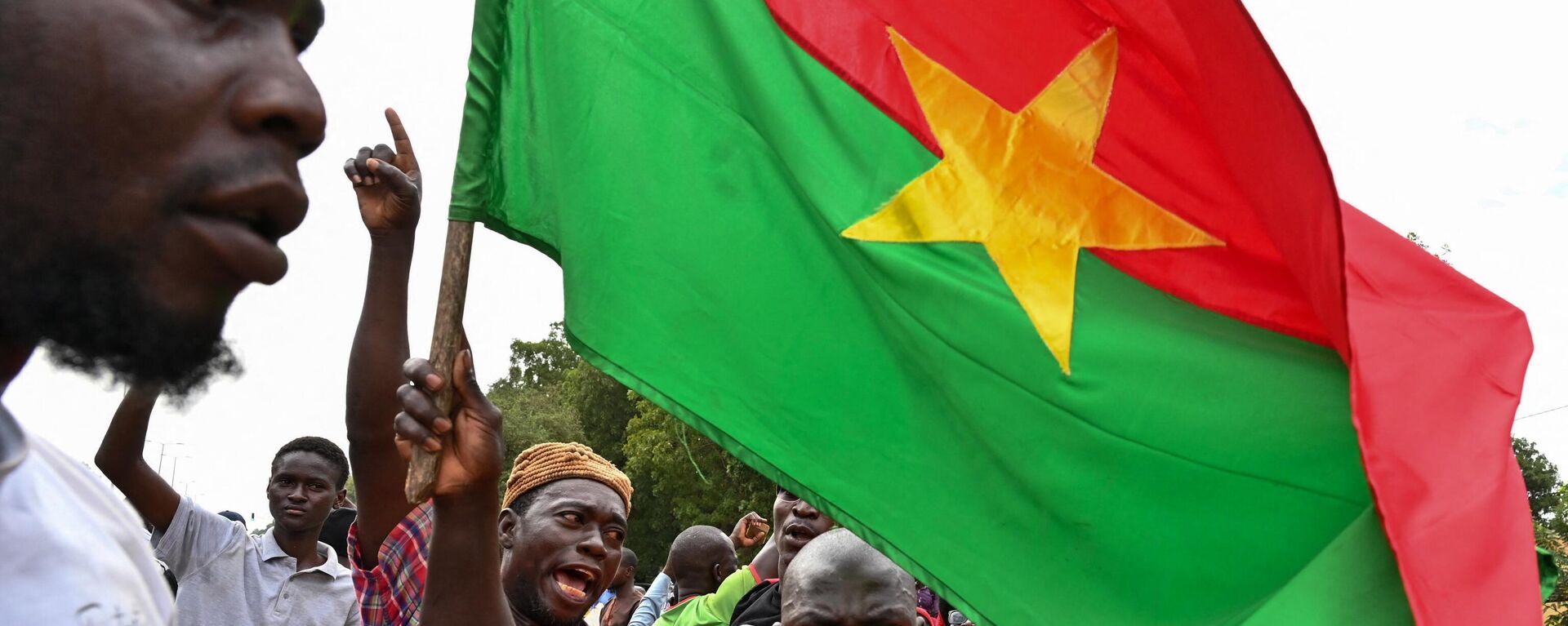 Supporters of Burkina Faso's new leader Ibrahim Traore hold a national flag during a demonstration near the national radio and television headquarters (RTB) in Ouagadougou on October 6, 2022 - Sputnik Africa, 1920, 31.07.2023