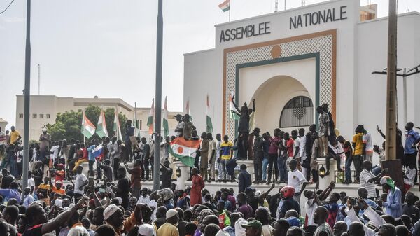 Supporters wave Nigerien's flags as they rally in support of Niger's junta in front of the National Assembly in Niamey on July 30, 2023.  - Sputnik Africa