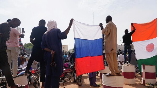 Des Nigériens brandissent un drapeau russe à Niamey (archives) - Sputnik Afrique