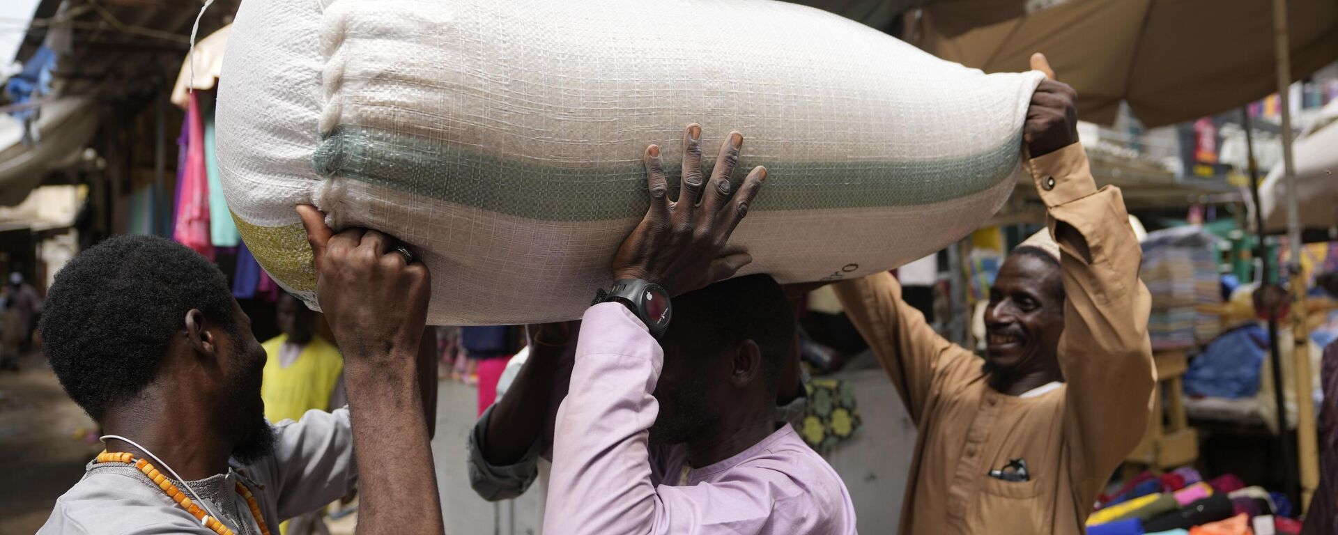 People balance a bag containing grains on a man's head at a market in Kano, Nigeria, Thursday, July 13, 2023.  - Sputnik Africa, 1920, 01.08.2023
