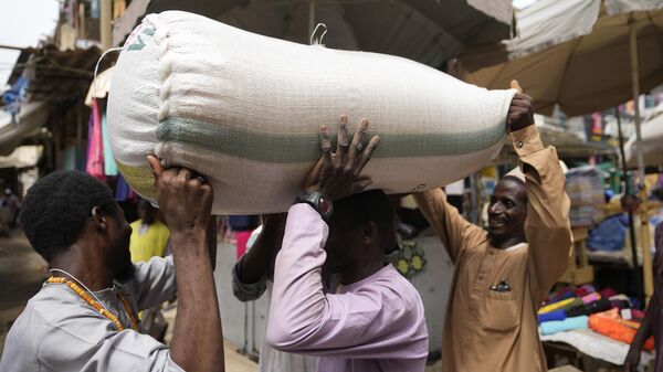 People balance a bag containing grains on a man's head at a market in Kano, Nigeria, Thursday, July 13, 2023.  - Sputnik Africa