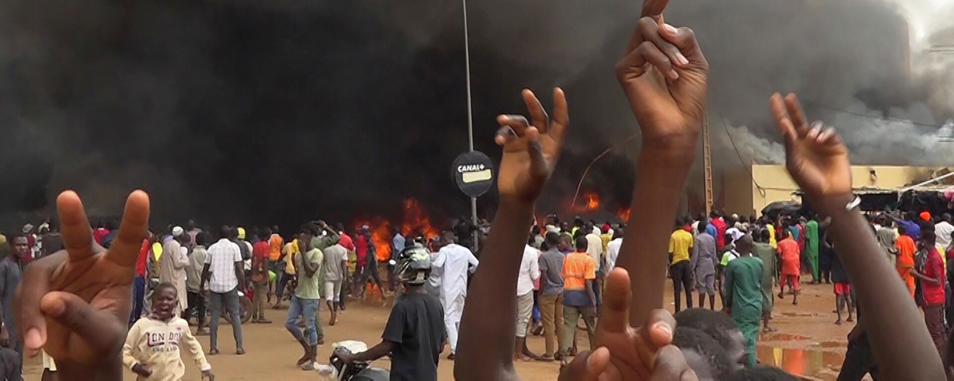 With the headquarters of the ruling party burning in the back, supporters of mutinous soldiers demonstrate in Niamey, Niger, Thursday, July 27 2023. - Sputnik Africa, 1920, 29.03.2024