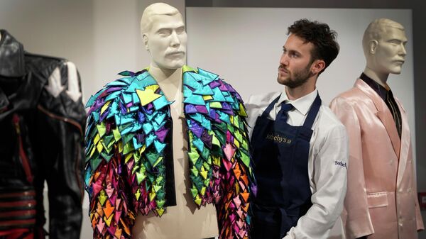 A Sotheby's employee displays the 1982 Rainbow Arrow Appliqué Satin Jacket at Sotheby's auction rooms in London - Sputnik Africa
