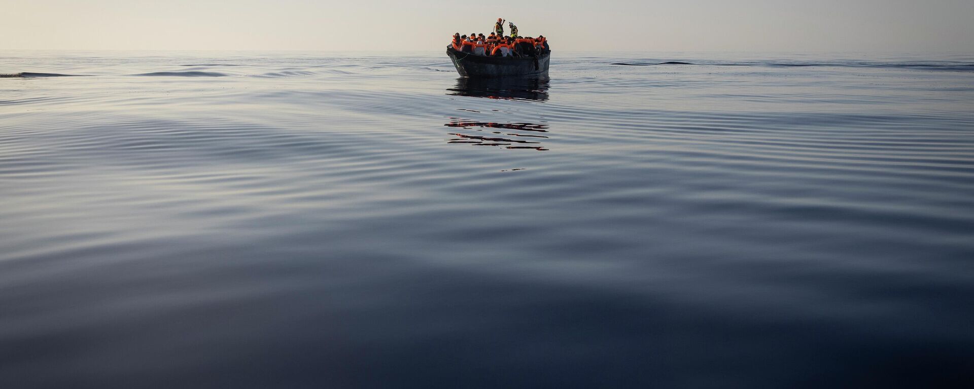 Migrants with life jackets provided by volunteers of the Ocean Viking, a migrant search and rescue ship run by NGOs SOS Mediterranee and the International Federation of Red Cross (IFCR), still sail in a wooden boat as they are being rescued, Aug. 27, 2022, in the Mediterranean sea - Sputnik Africa, 1920, 06.08.2023