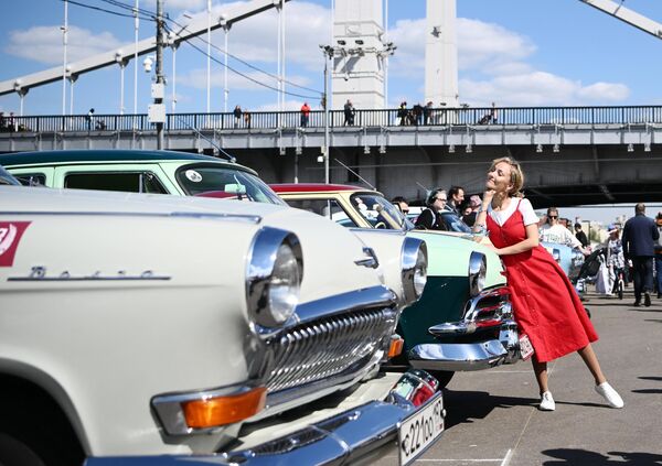 A girl is photographed by cars before the start of the retro rally &quot;Capital&quot; on the Pushkin Embankment in Moscow&#x27;s Gorky Park. - Sputnik Africa