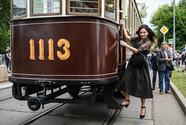 A young lady hangs on for a historic tram at the retro transport parade in Moscow. - Sputnik Africa
