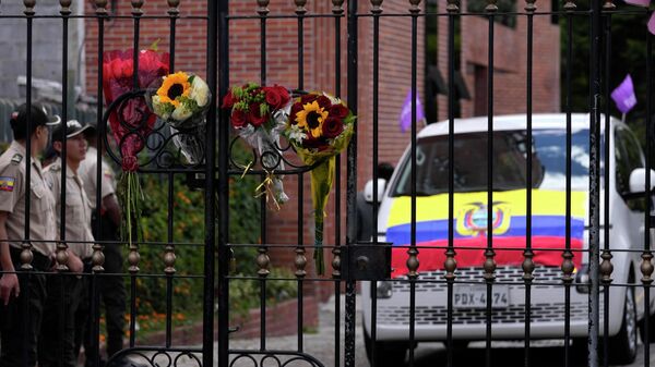 Flowers hang on the cemetery fence where police stand by a vehicle that is part of a funeral procession that will take the remains of slain presidential candidate Fernando Villavicencio - Sputnik Africa