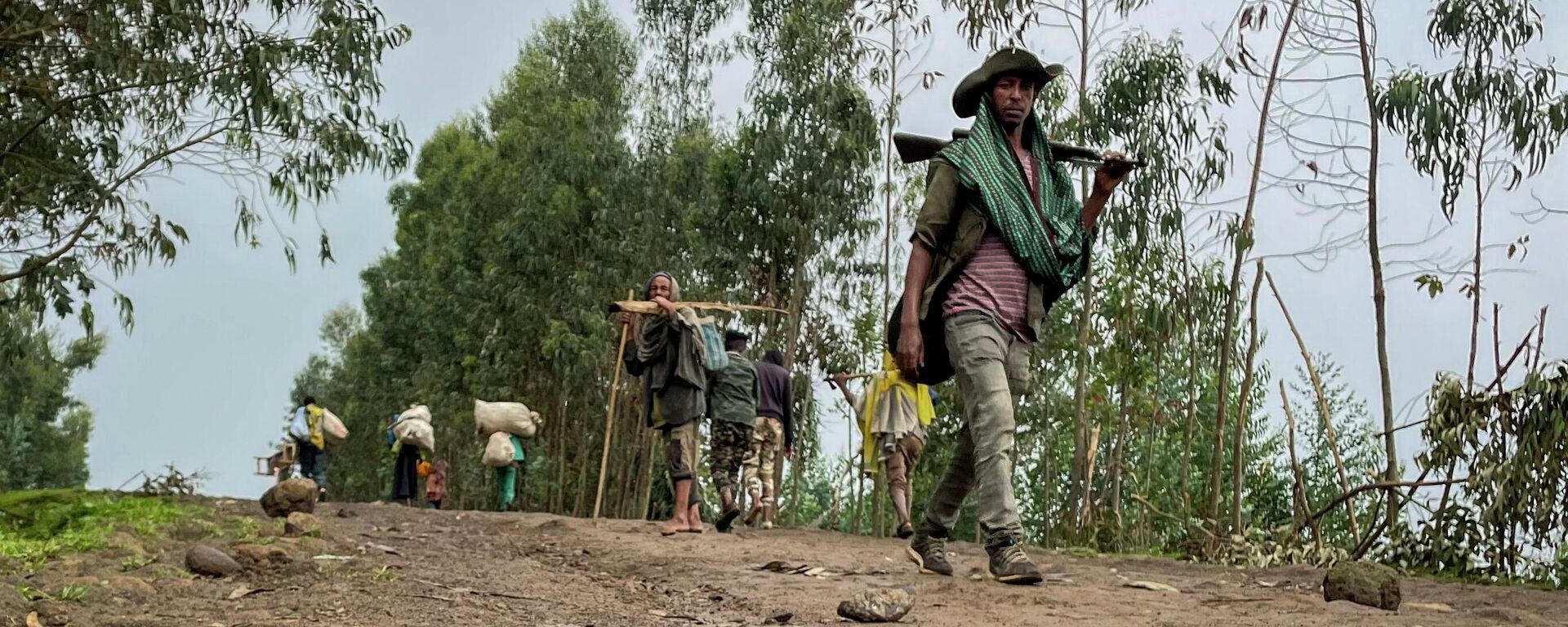 An unidentified armed militia fighter walks down a path as villagers flee with their belongings in the other direction, near the village of Chenna Teklehaymanot, in the Amhara region of northern Ethiopia Thursday, Sept. 9, 2021.  - Sputnik Africa, 1920, 12.08.2023