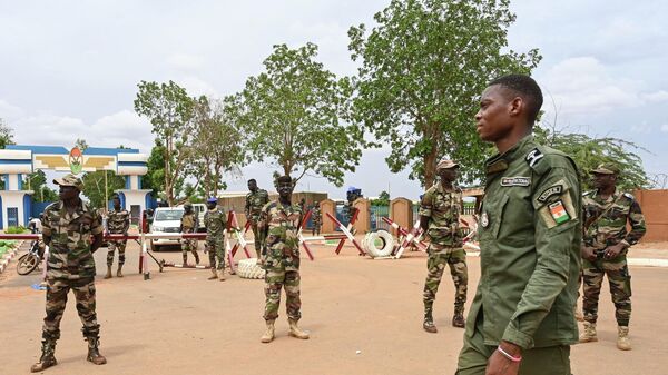 Nigerien soldiers stand guard as supporters of Niger's National Council for the Safeguard of the Homeland (CNSP) gather for a demonstration in Niamey on August 11, 2023 near a French airbase in Niger. - Sputnik Africa